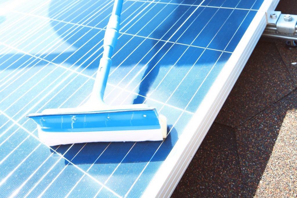 A blue squeegee is cleaning the surface of a solar panel in Brisbane, highlighting the maintenance process to keep solar panels efficient and free from dirt.