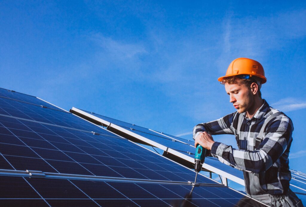 Solar installer securing solar panels with a power drill on a rooftop in the Sunshine Coast, showcasing skilled installation services.