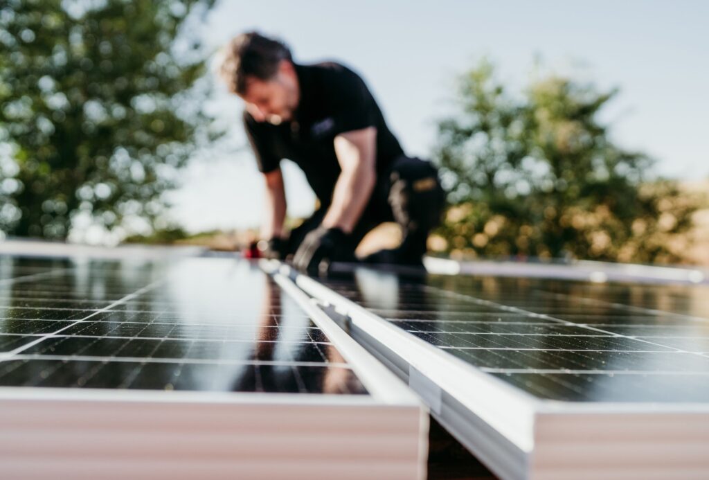 5 Reasons Sunshine Coast Businesses Are Switching to Solar 1 Worker installing solar panels on a roof, showcasing professional solar installation services in Brisbane and the Sunshine Coast.
